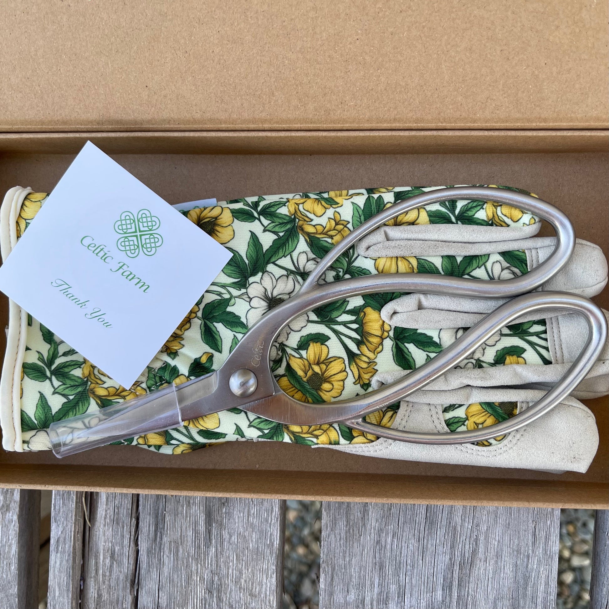 The Celtic Farm Garden Gift Box with green and yellow gloves and gardening snips, perfect for outdoor gardening tasks.