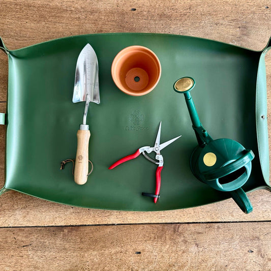 The Celtic Farm’s Potting Mat – Waterproof For Tidy Gardening keeps your trowel, terracotta pot, red-handled shears, and green watering can organized and compactly stored on any surface.