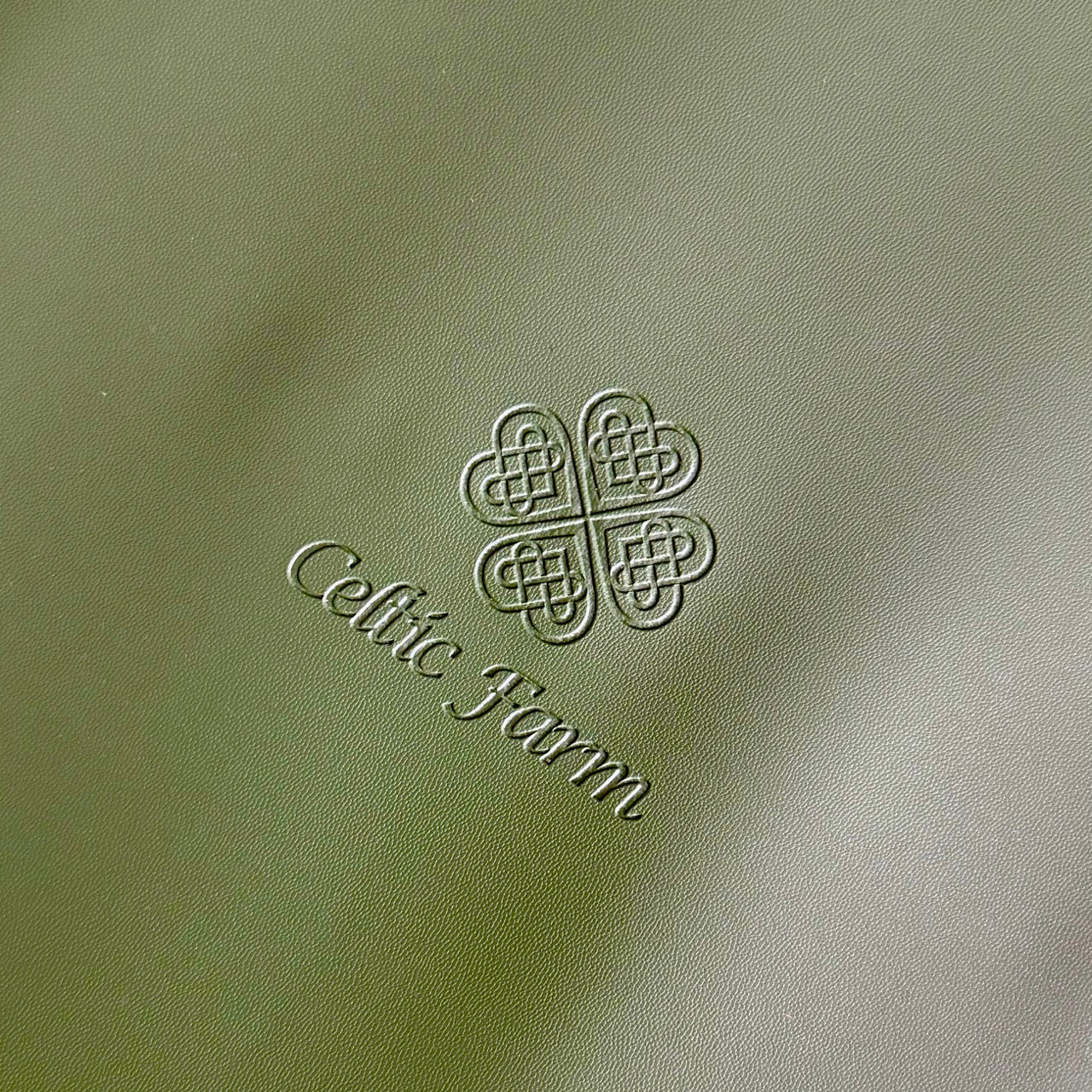The Celtic Farm’s Potting Mat—Waterproof For Tidy Gardening—features a green leather indoor/outdoor design with a Celtic knot above “Celtic Farm” in elegant script, and is easy to clean and store compactly.
