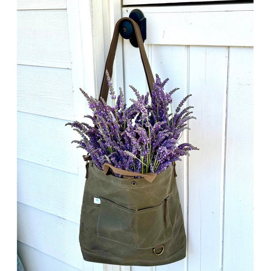 The Celtic Farm’s Gardener’s Multipurpose Shoulder Bag hangs by the door, filled with blooming lavender—ideal for organizing tools, market finds, or harvests after a day in the garden.