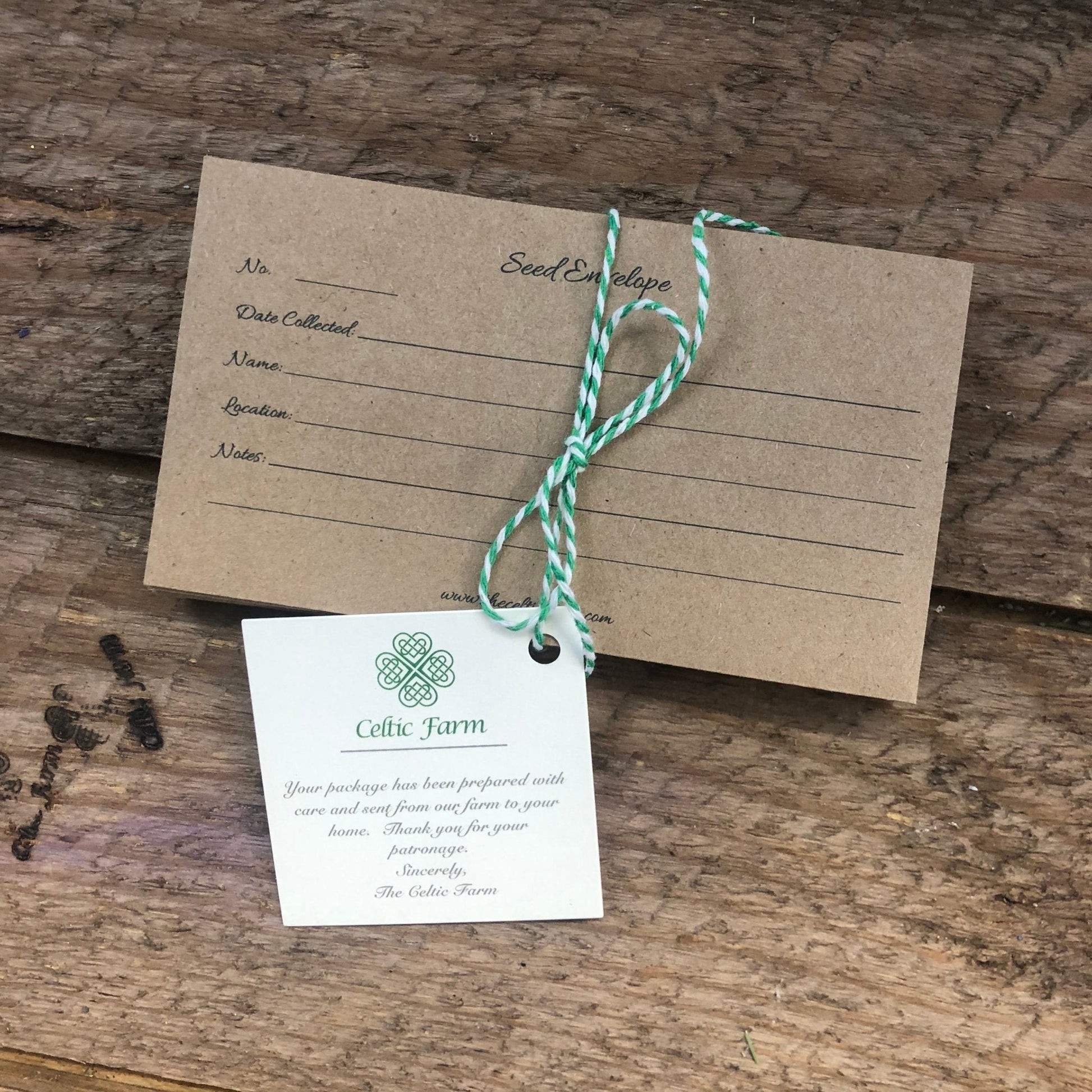 A brown seed envelope from The Celtic Farm’s Seed Collection sits on wood, tied with green and white string. A Celtic Farm tag with a thank you note and Celtic knot makes it a thoughtful gift for gardeners.