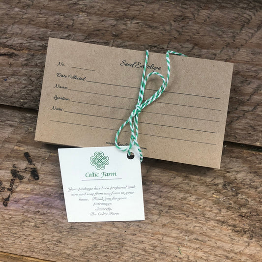 A brown seed envelope from The Celtic Farm’s Seed Collection sits on wood, tied with green and white string. A Celtic Farm tag with a thank you note and Celtic knot makes it a thoughtful gift for gardeners.