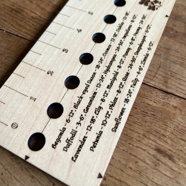 The Celtic Farm’s American Hardwood Seed and Bed Ruler, made in the US from American lumber, features labeled holes and flower names with planting depths—perfect for precise gardening.