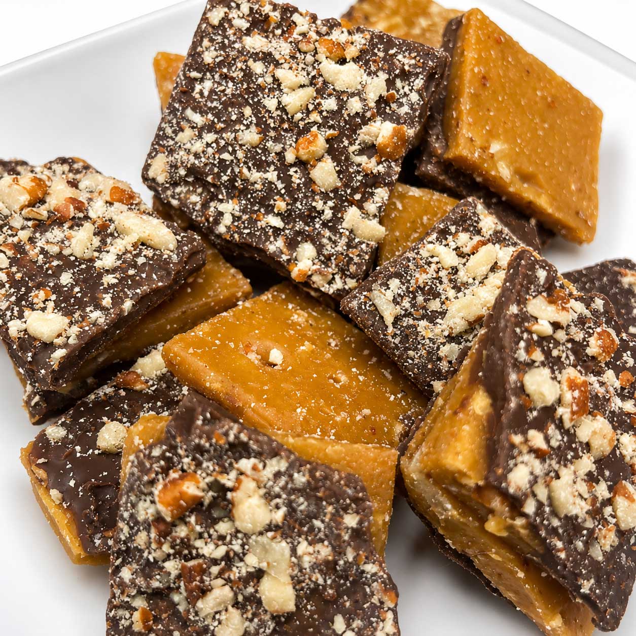 Homemade Barb's Buttery Milk Chocolate Toffee with mixed nuts in an 8 oz package, displayed on a rustic surface.