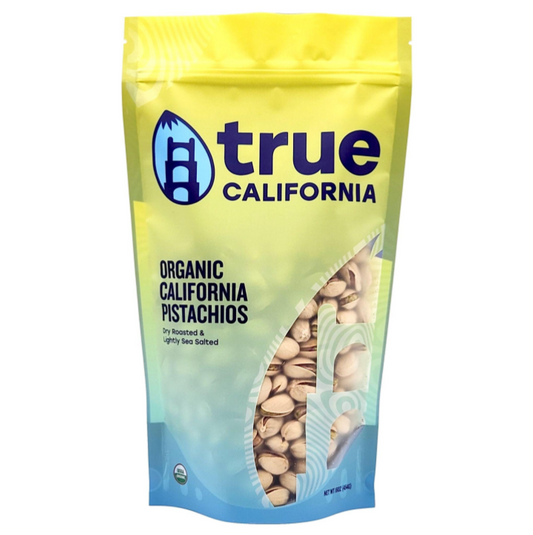 Dry roasted organic pistachios with light sea salt in a clear bowl, showcasing the green nuts and salted shells.