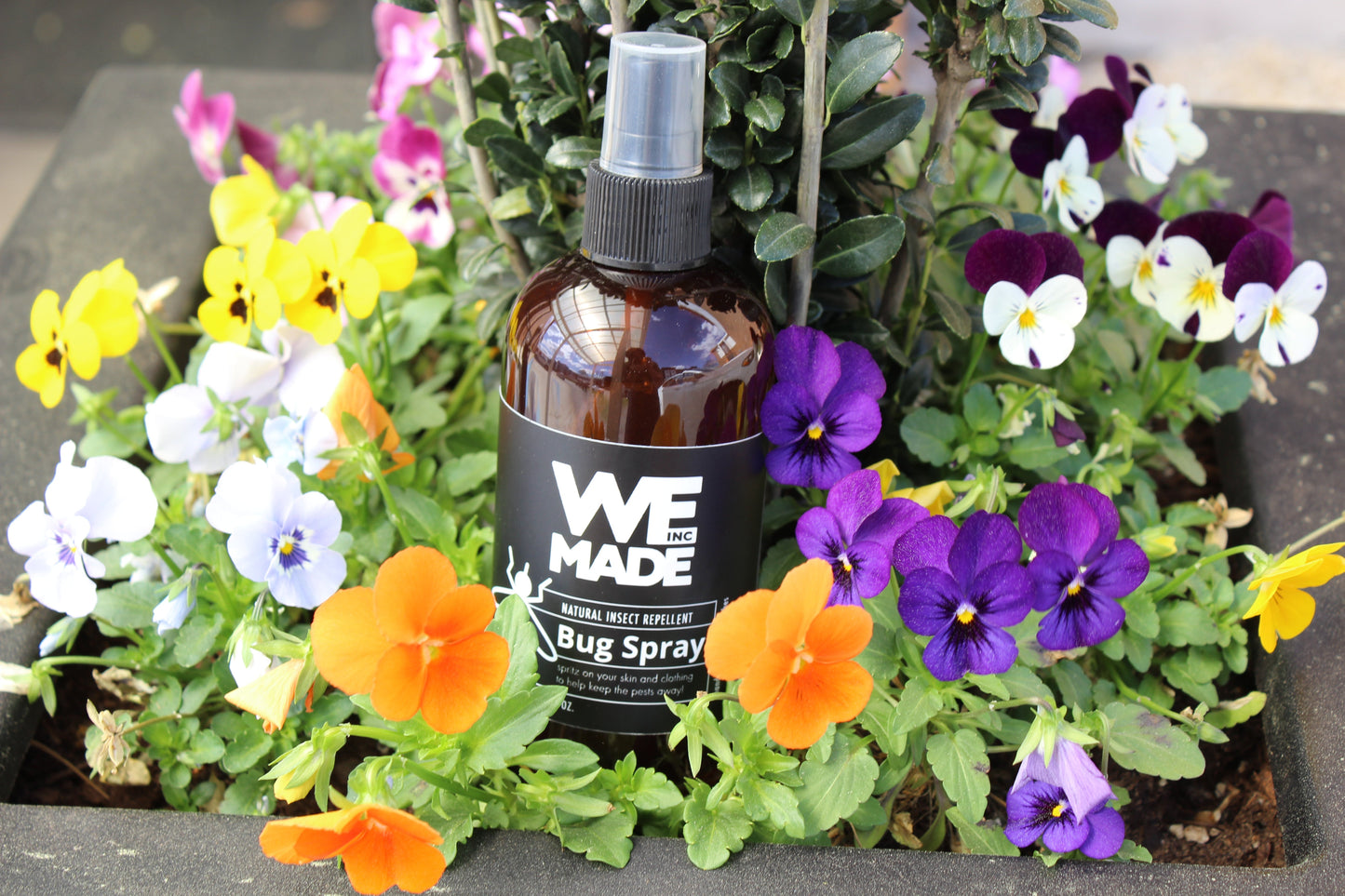 Bottle of WE Made natural insect repellent bug spray with spray nozzle, designed to repel bugs naturally.
