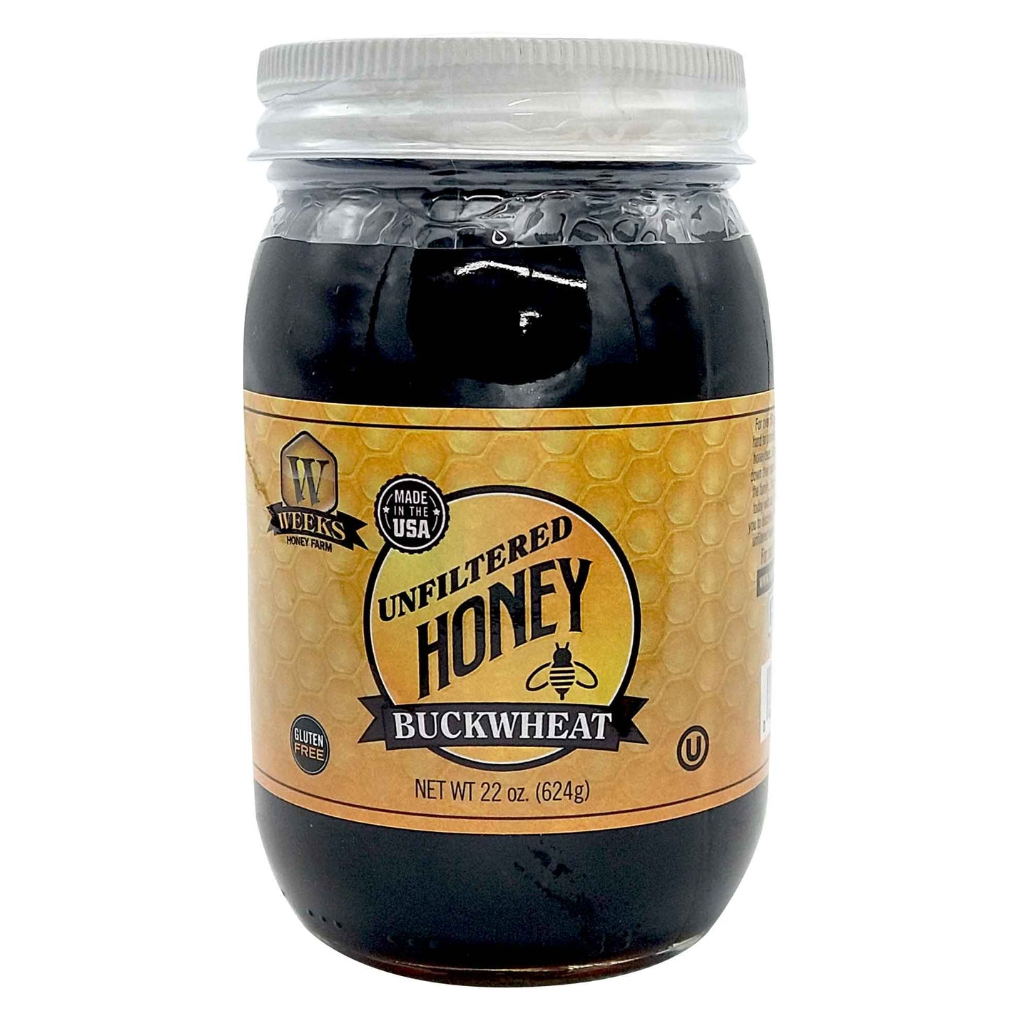 A 22oz jar of Weeks Honey Farm Raw Buckwheat Honey features a clear plastic lid, honeycomb label, and contains pure, gluten-free, antioxidant-rich, dark honey with robust molasses flavor—perfect for coffee or waffles. Made in the USA.
