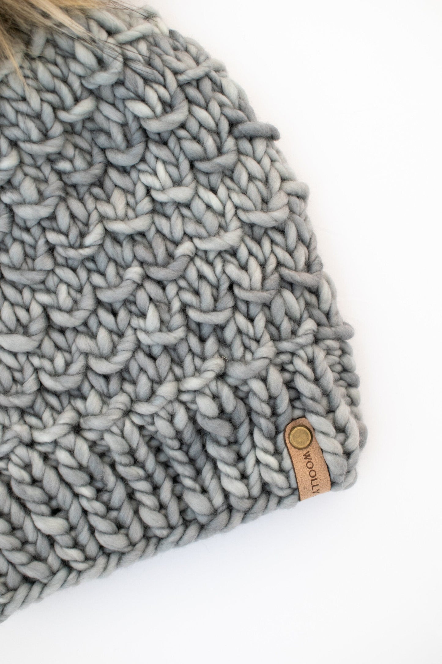 Gray Merino Wool Knit Hat with Faux Fur Pom Pom by Woolly Bear Knits, showing the cozy wool hat with fluffy pom pom detail.
