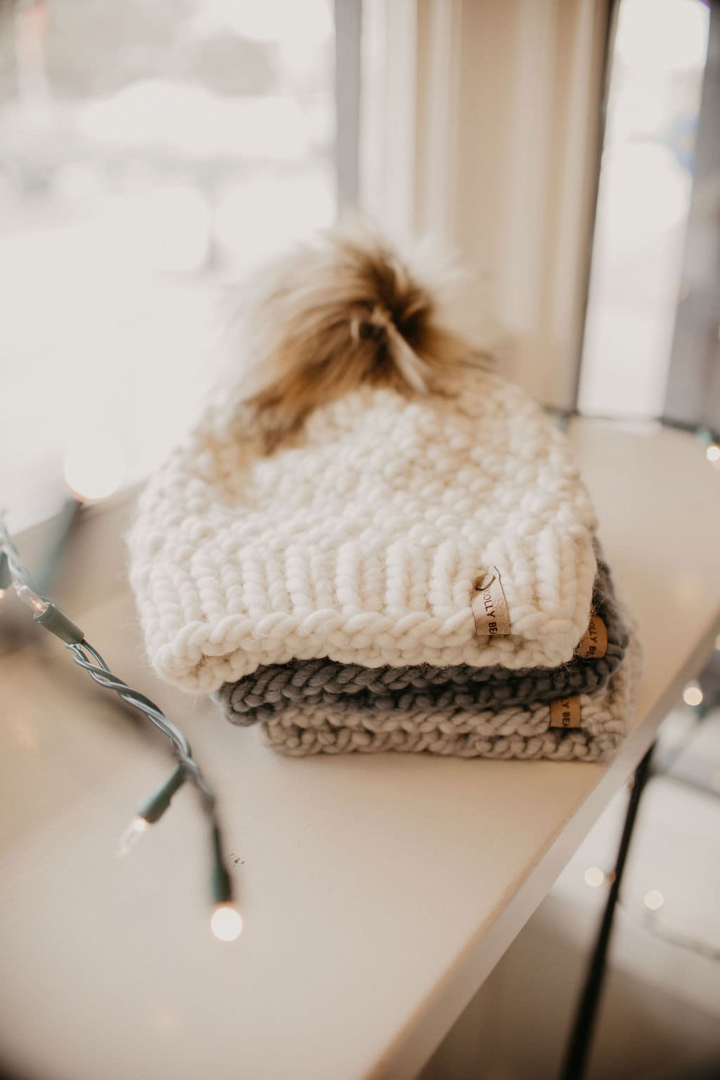 Ivory Peruvian wool knit hat with faux fur pom pom by Woolly Bear Knits, featuring a cozy, textured design and warm ear coverage.
