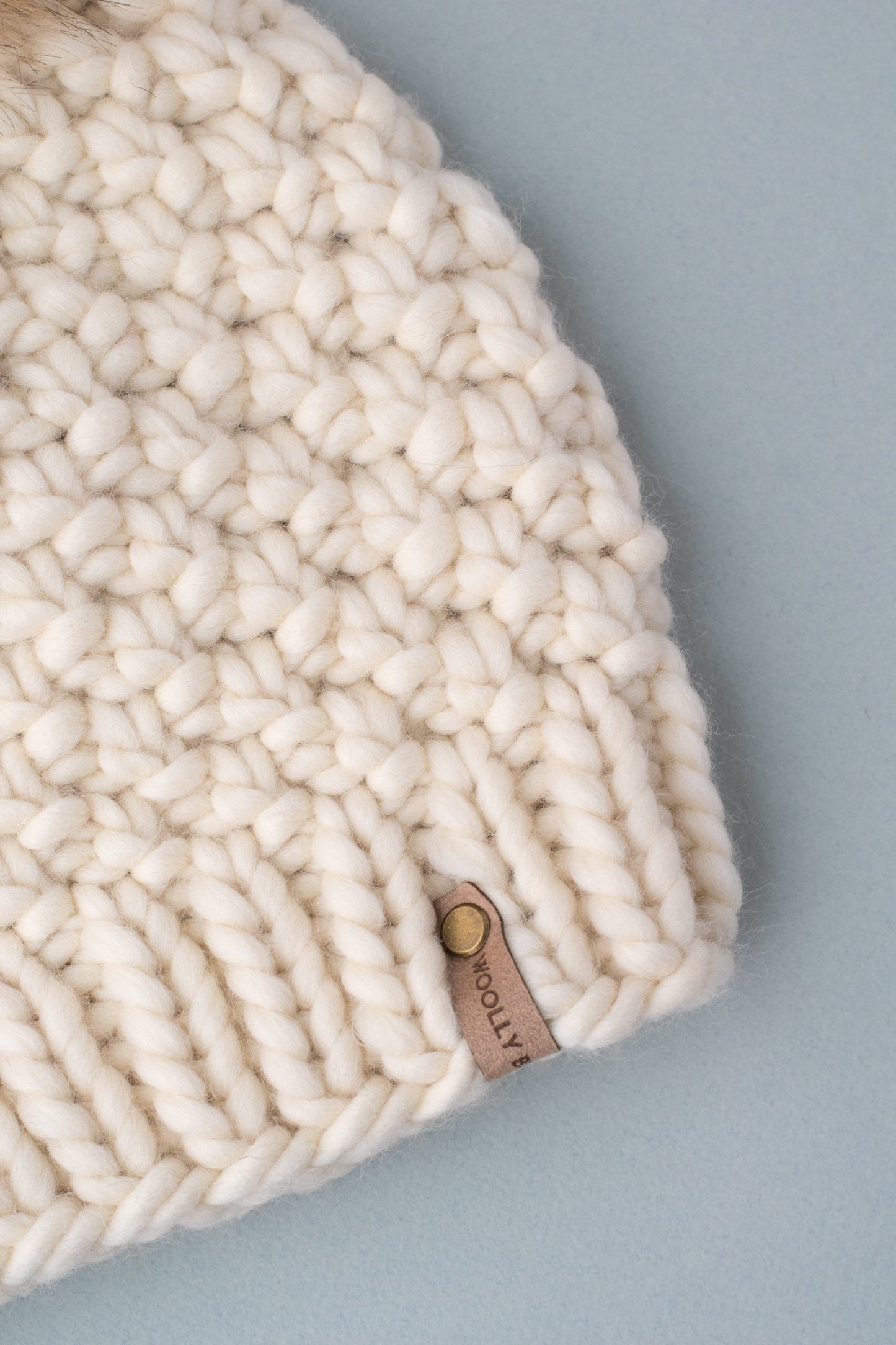 Ivory Peruvian wool knit hat by Woolly Bear Knits with a fluffy faux fur pom pom on top, cozy and stylish winter accessory.