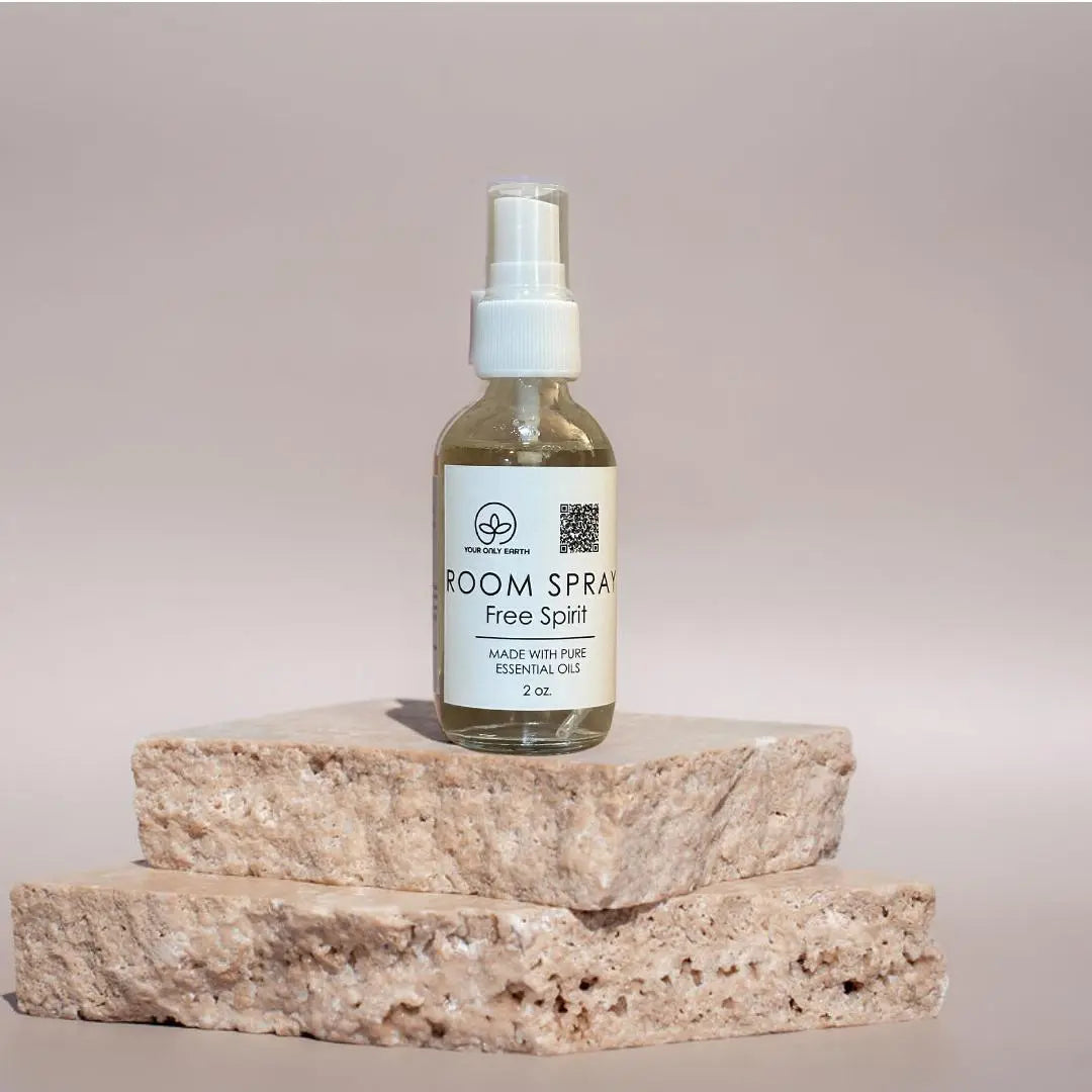 A 2 oz Room Spray from Your Only Earth, made with pure essential oils, sits gracefully on two beige stone slabs against a neutral background, embodying tranquility and natural essence for those who value authentic room sprays.