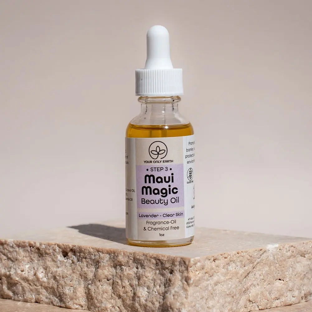 A glass dropper bottle of Your Only Earth Maui Magic Beauty Oil sits on a stone block. This 1oz, lavender-infused oil is fragrance-free, chemical-free, and ideal for acne and rosacea; displayed against a beige backdrop.