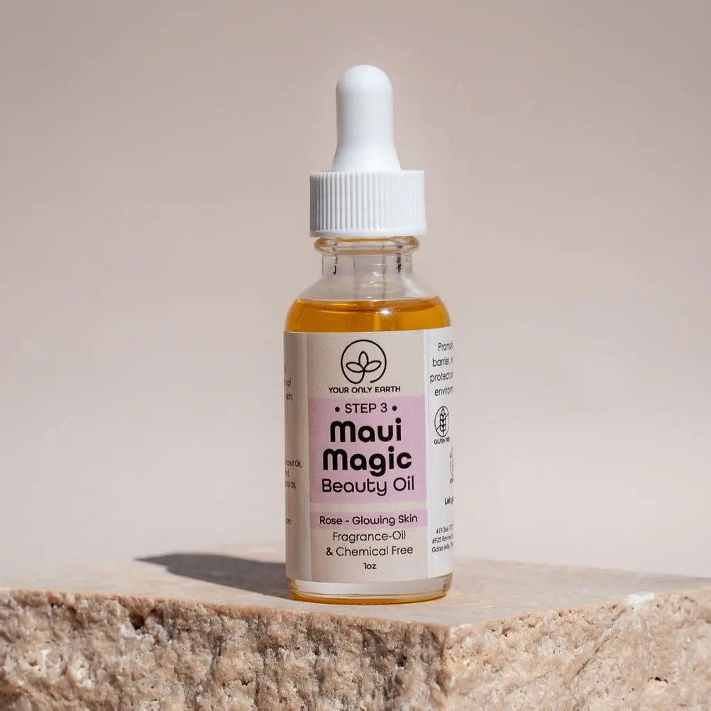 A clear glass dropper bottle of Your Only Earth Maui Magic Beauty Oil for acne and rosacea sits on a stone surface against a beige background. The label reads Rose - Glowing Skin, Fragrance & Chemical Free, 1 oz.