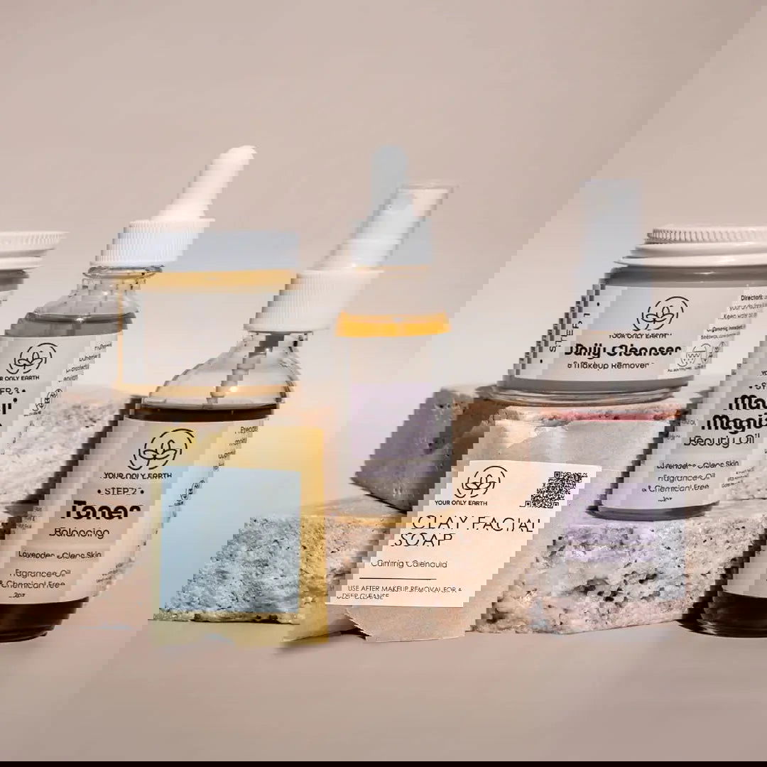 Three Dewy Skincare Set bottles and a box from Your Only Earth rest on a stone slab, their labels partially obscured by glitch-like digital effects—evoking eco-friendly skincare powered by plant extracts.