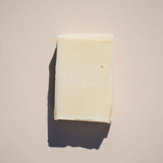 A 3.75 oz bar of Your Only Earths Lavender Soap rests on a light beige surface. Its a rectangular shape with slightly rounded corners casting a soft left shadow. The soaps smooth texture, with slight imperfections, gives it a handcrafted feel.