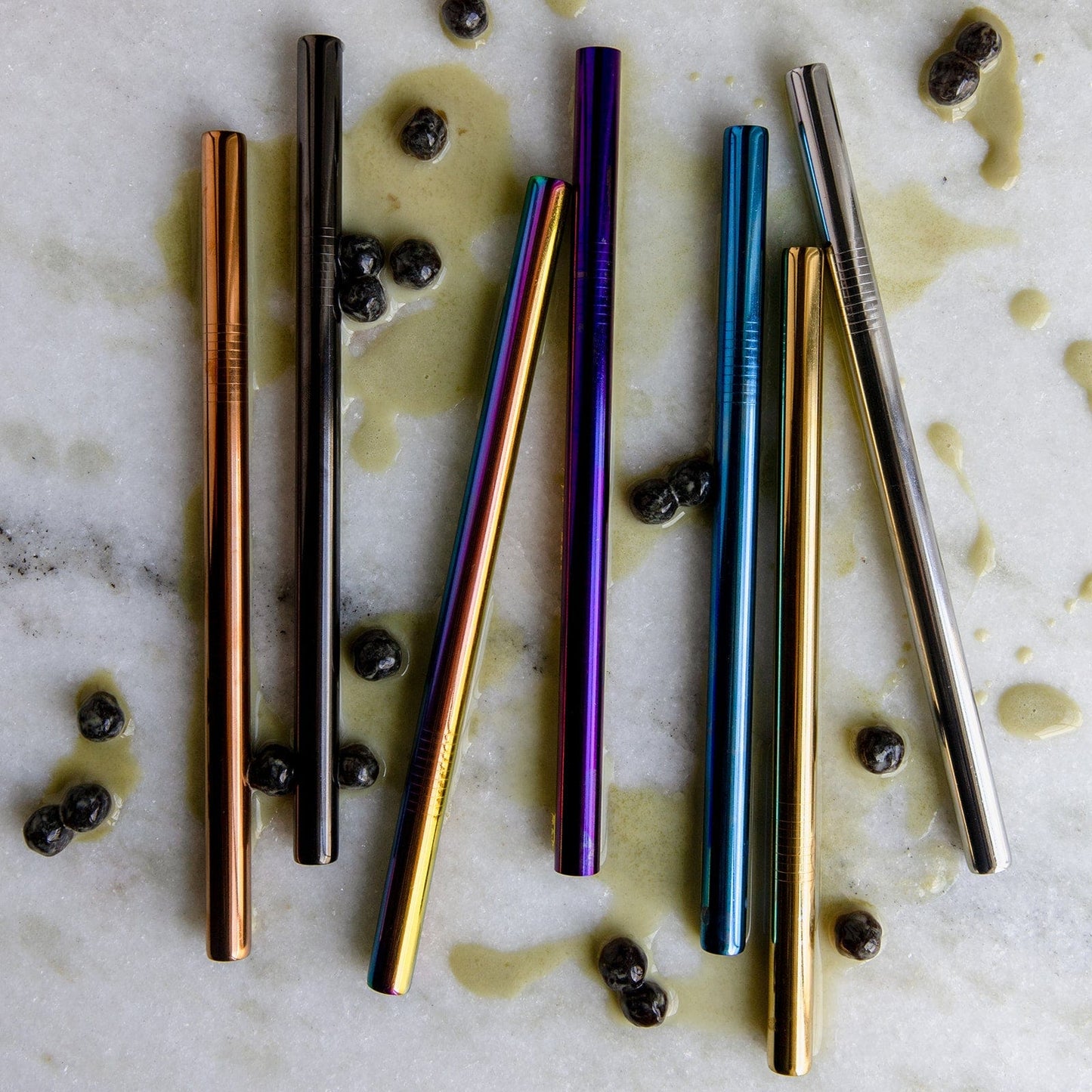 ZeroWasteStore.com's Stainless Steel Straw – Straight, Bent, or Boba Style – shines on white marble with boba pearls and splashes, offering a vibrant and plastic-free way to enjoy zero waste sipping.