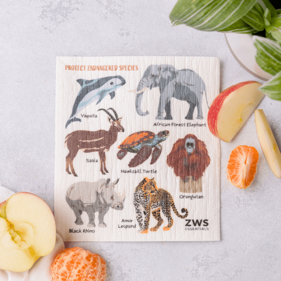 The ZeroWasteStore.com Swedish Dish Cloth features illustrations of endangered species like the Vaquita and African Forest Elephant, shown with apples and an orange. It's an eco-friendly paper towel replacement for your kitchen.