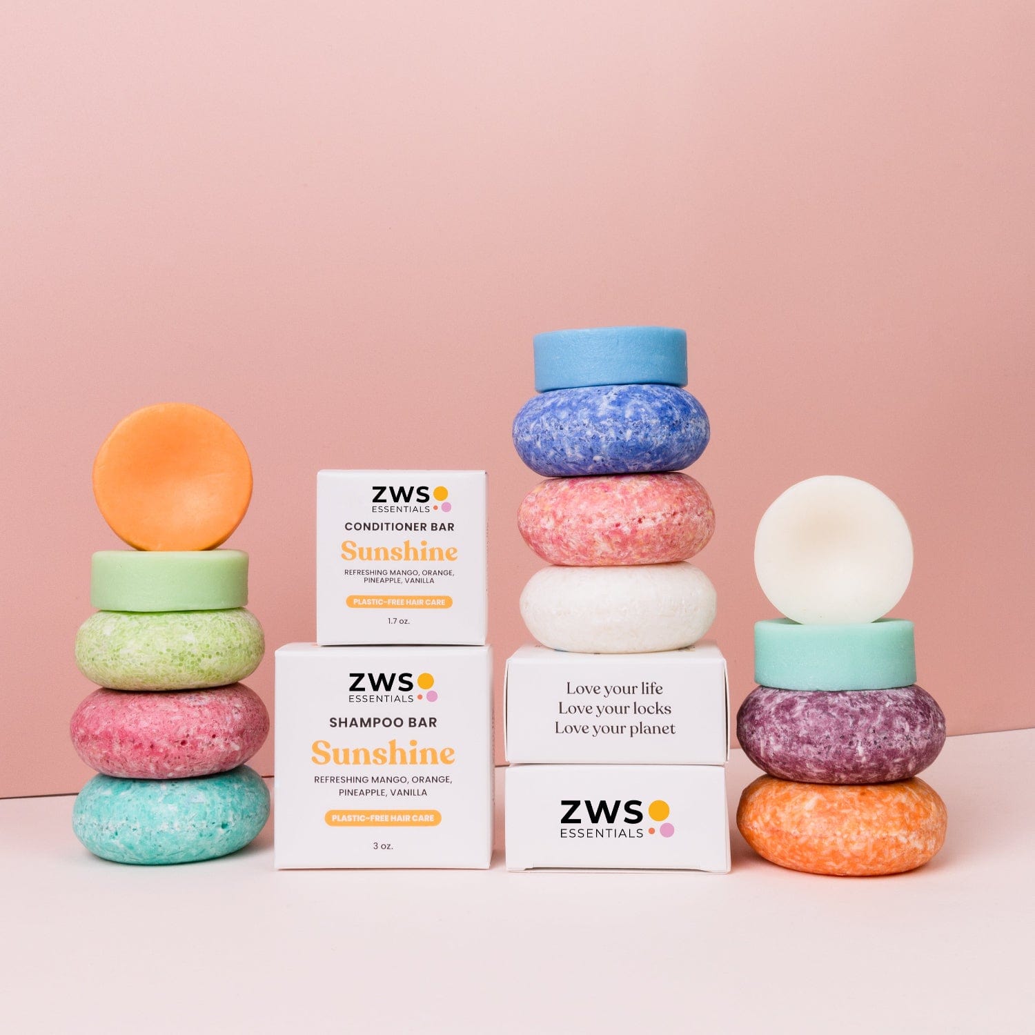 Colorful round Shampoo Bars from ZeroWasteStore.com are stacked beside white boxes on a pink background, highlighting this zero waste hair care option that lets you love your locks and the planet.