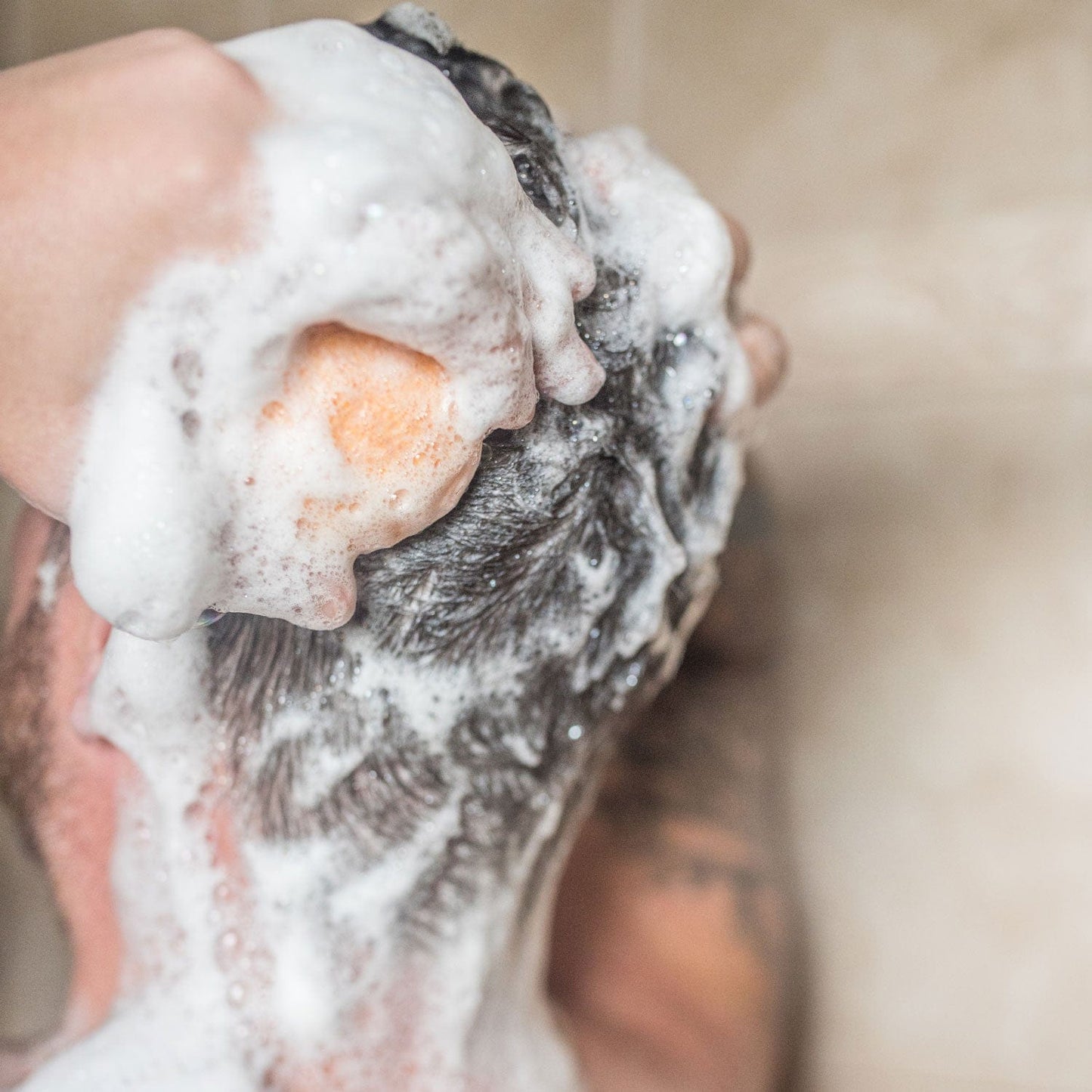A close-up of someone using a Shampoo Bar from ZeroWasteStore.com, massaging rich foam onto wet hair. The blurred background highlights the lathered scalp, emphasizing an eco-friendly, zero waste hair care routine.