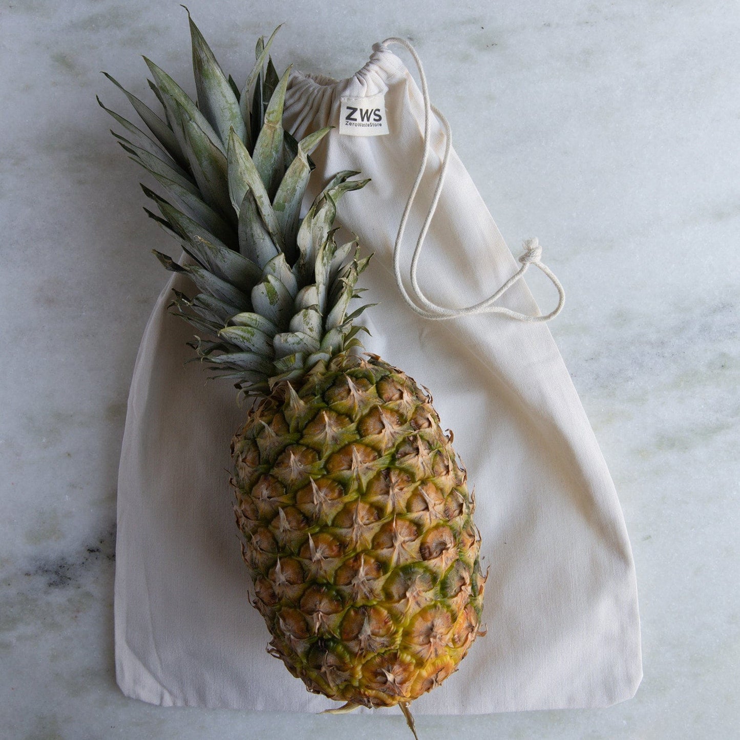 A whole pineapple sits on a ZeroWasteStore.com Muslin Produce Bag—an eco-friendly, reusable bag in multiple sizes—showcasing a stylish choice for your zero waste grocery lifestyle.