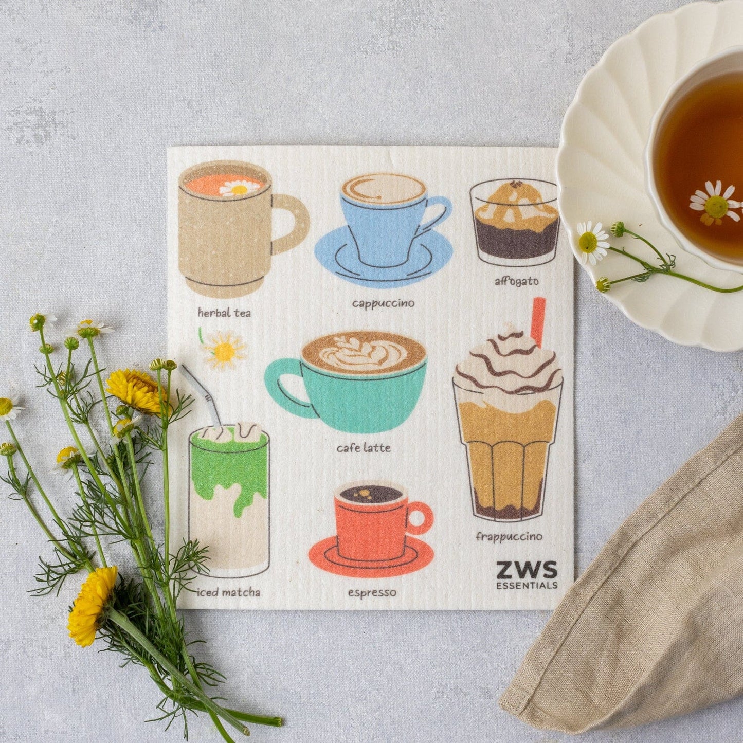 The ZeroWasteStore.com Swedish Dish Cloth, an eco-friendly paper towel alternative, features illustrated drink cups like herbal tea, cappuccino, and affogato—perfect beside your tea, flowers, or a napkin.