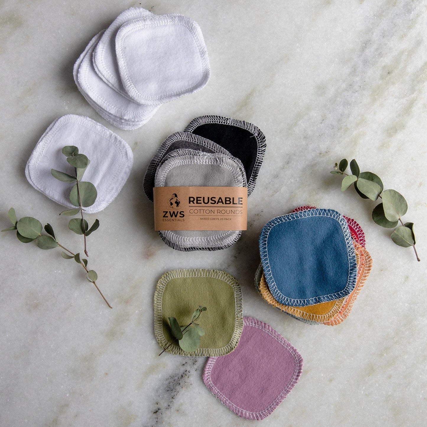 ZeroWasteStore.com's Reusable Cotton Rounds in white and assorted colors are displayed on marble with eucalyptus, offering a sustainable choice for anyone seeking reusable facial rounds and supporting a zero waste lifestyle.