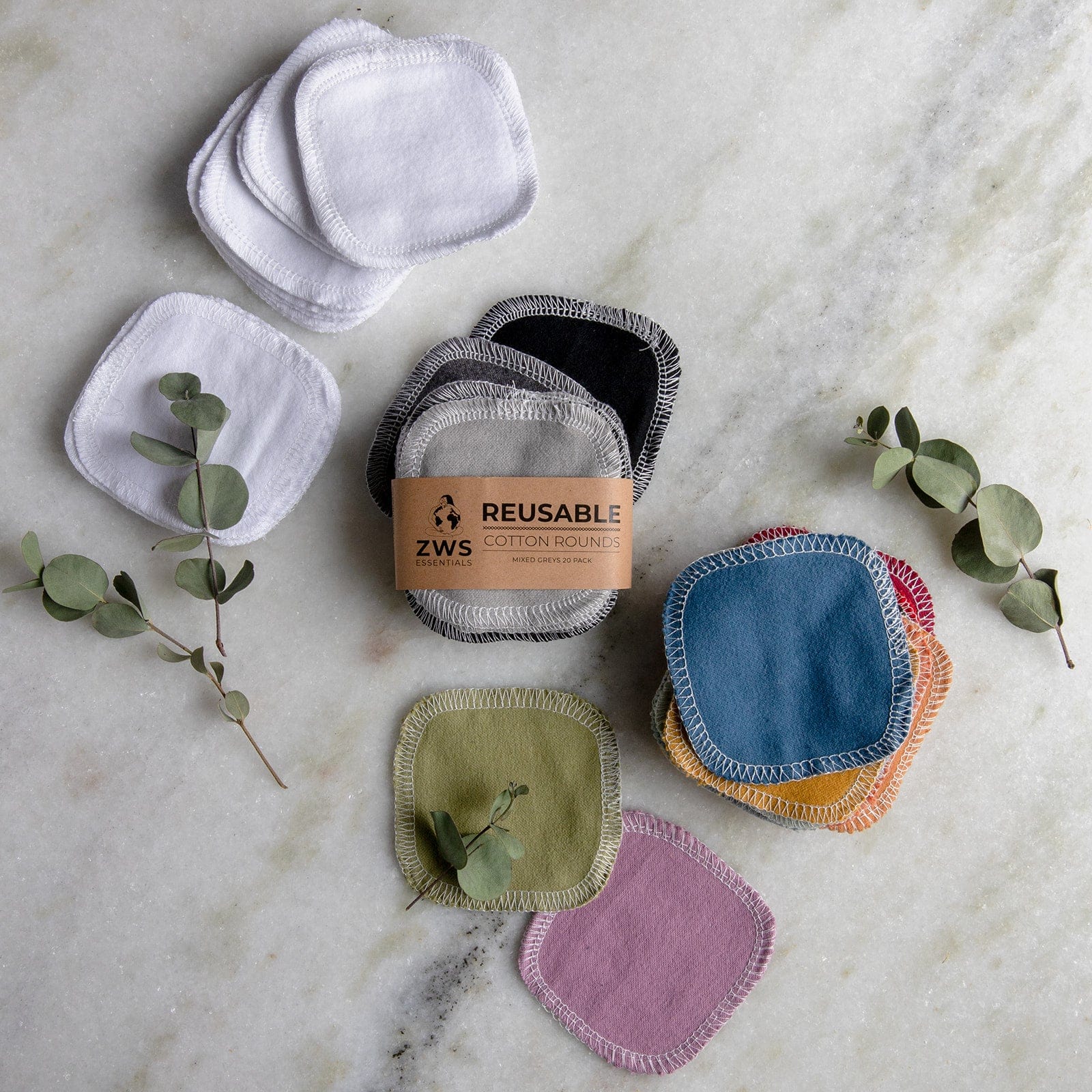 ZeroWasteStore.com's Reusable Cotton Rounds in white and assorted colors are displayed on marble with eucalyptus, offering a sustainable choice for anyone seeking reusable facial rounds and supporting a zero waste lifestyle.