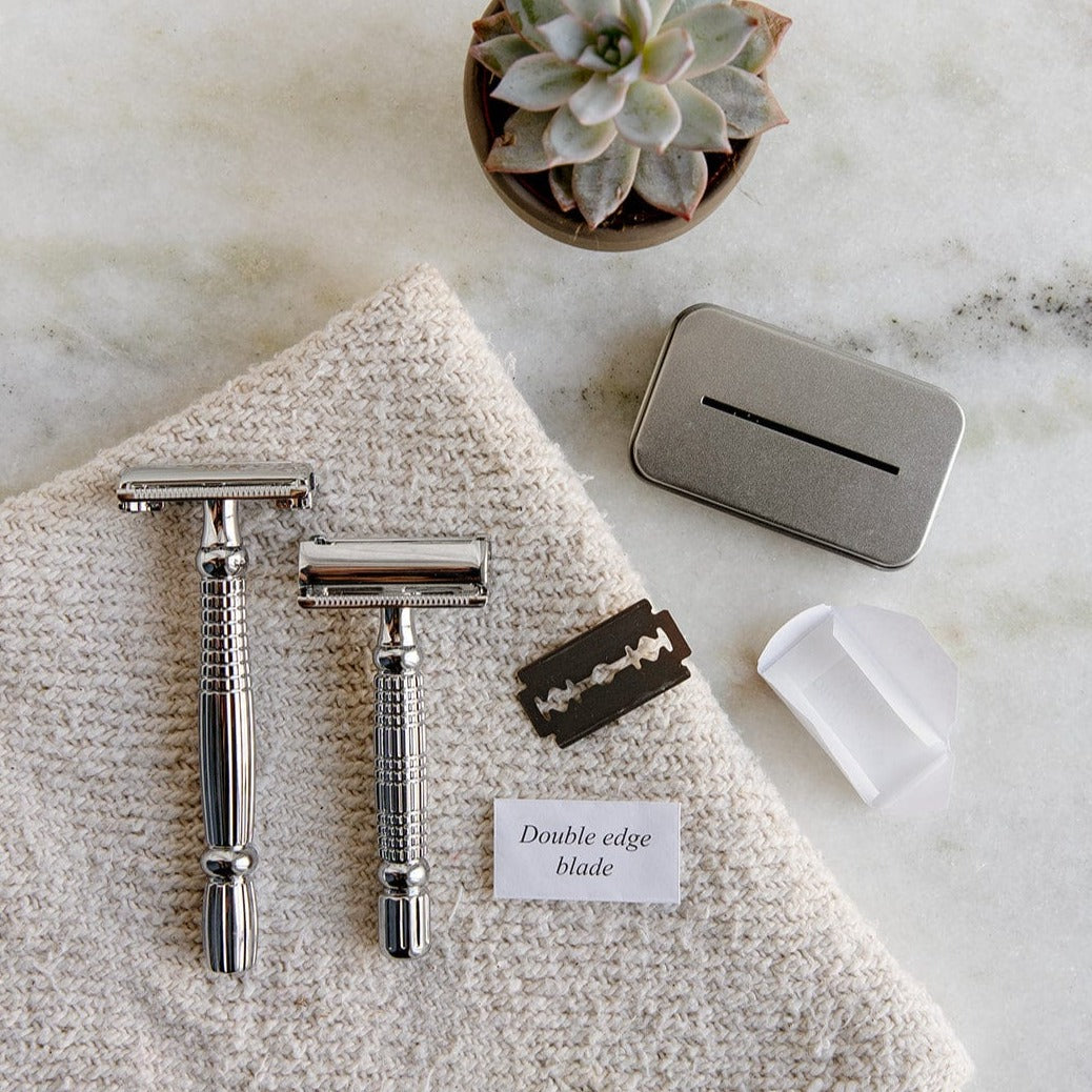 The ZeroWasteStore.com Zero Waste Safety Razor, with a single blade and 10 free blades, is displayed on marble with grooming essentials and a succulent for sustainable, plastic-free shaving.