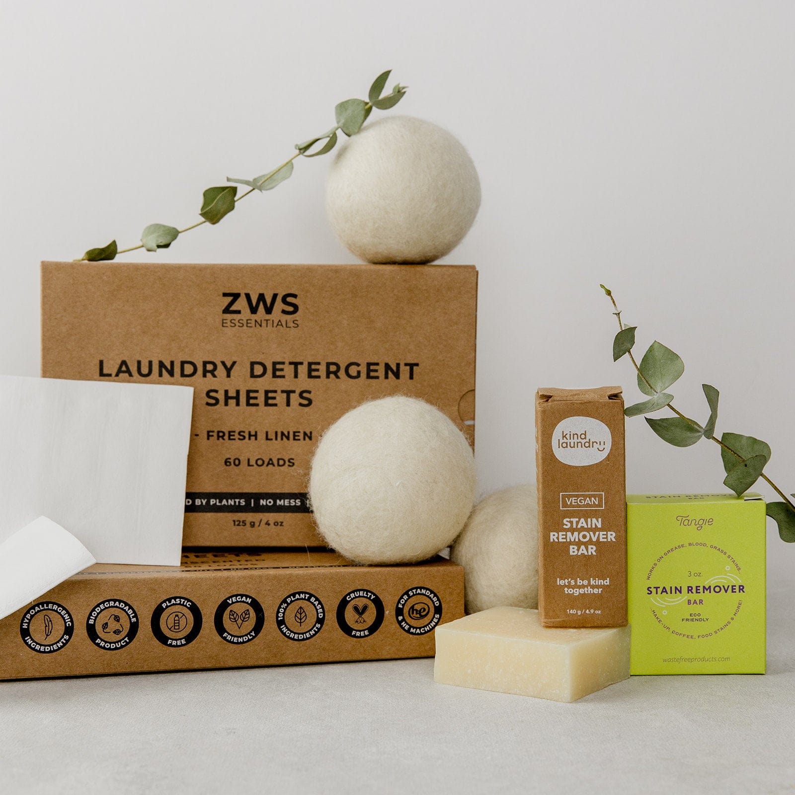 ZeroWasteStore.com’s eco-friendly set features Laundry Detergent Sheets, wool dryer balls, two stain remover bars, a white cloth, and eucalyptus sprigs—all on a neutral background.